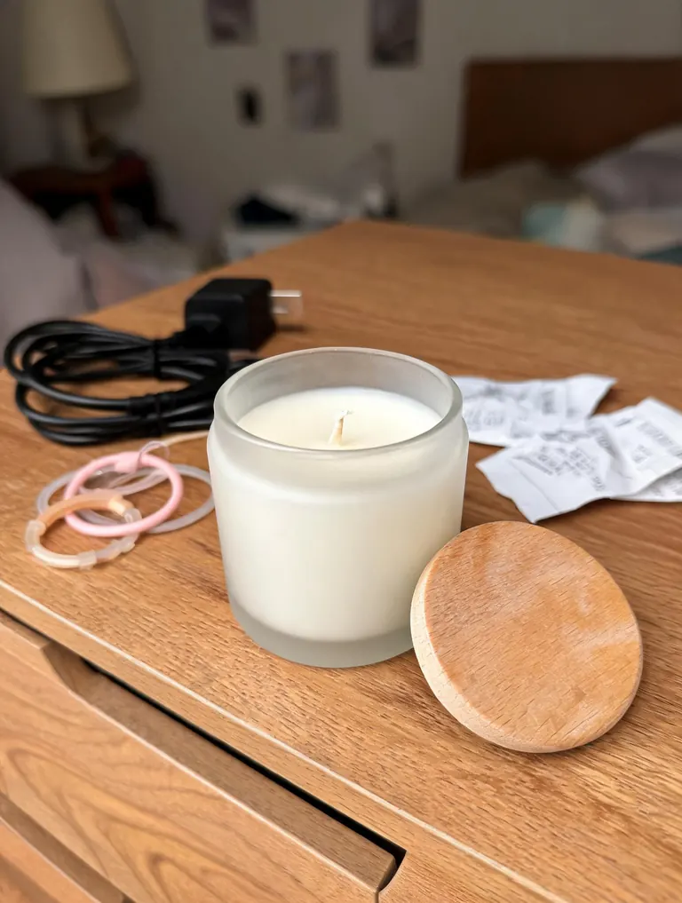 Original phone photo of a candle in a frosted glass jar on a cluttered dresser